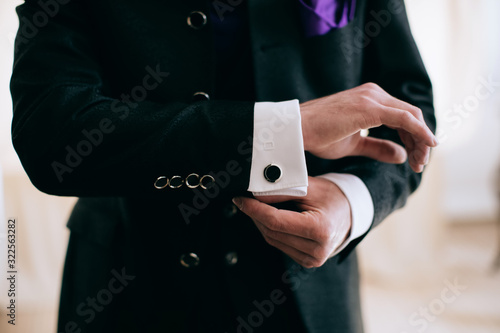  A man in a business suit fastens a button on his sleeve. Business concept.