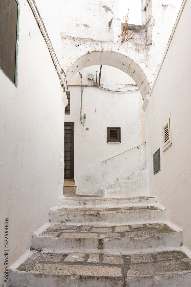 small alley with white houses and steps in historical town Ostuni, Italy