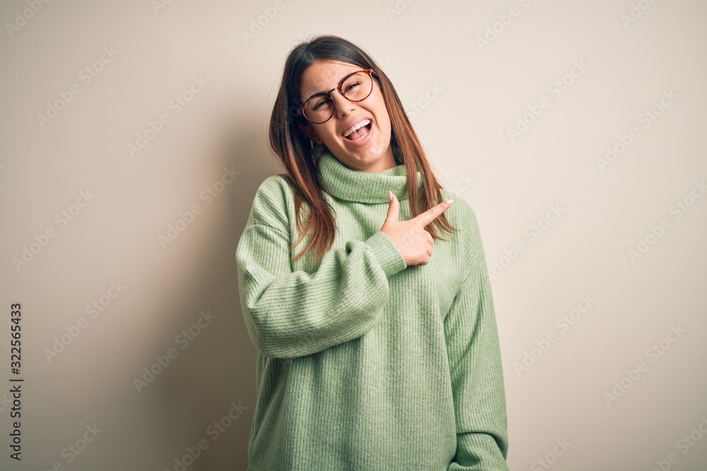Young beautiful woman wearing casual sweater standing over isolated white background cheerful with a smile of face pointing with hand and finger up to the side with happy and natural expression Young beautiful woman wearing casual sweater standing over isolated white background cheerful with a smile of face pointing with hand and finger up to the side with happy and natural expression