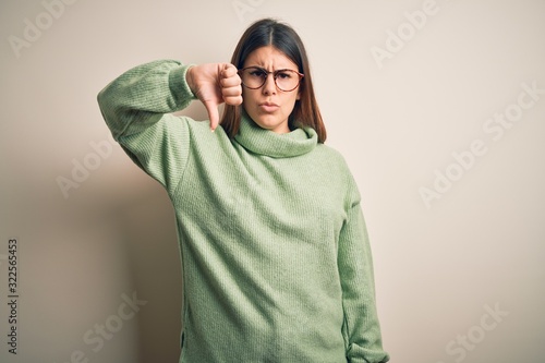 Young beautiful woman wearing casual sweater standing over isolated white background looking unhappy and angry showing rejection and negative with thumbs down gesture. Bad expression. © Krakenimages.com