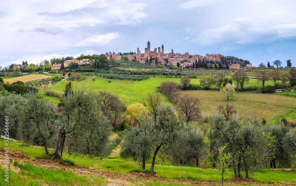 Amazing spring landscape with green rolling hills and old town of San Gimignano in the distance, Tuscany, Italy