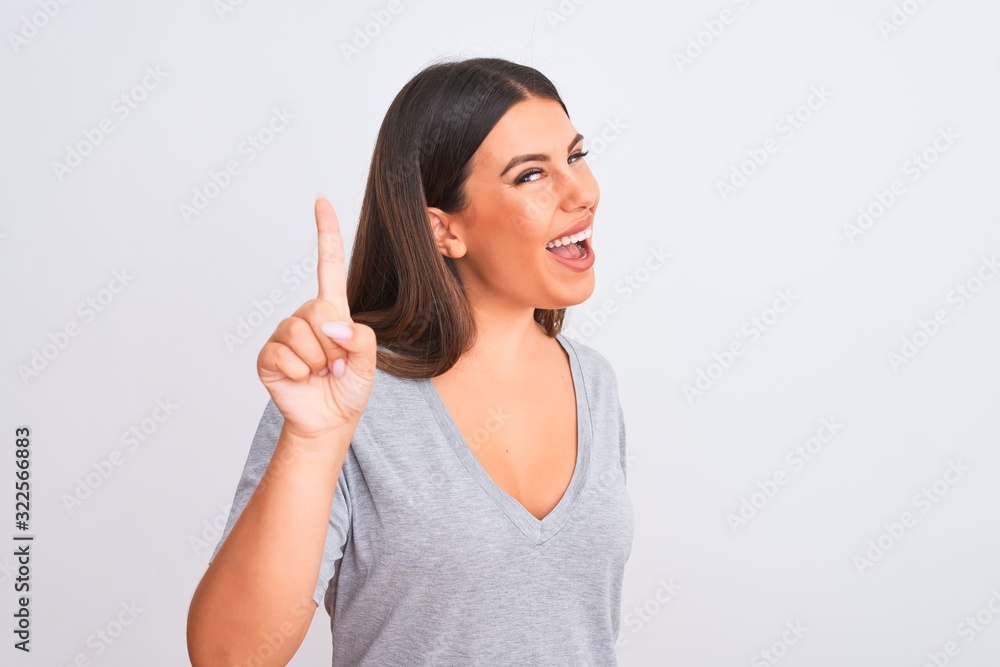 Portrait of beautiful young woman standing over isolated white background pointing finger up with successful idea. Exited and happy. Number one. Portrait of beautiful young woman standing over isolated white background pointing finger up with successful idea. Exited and happy. Number one.