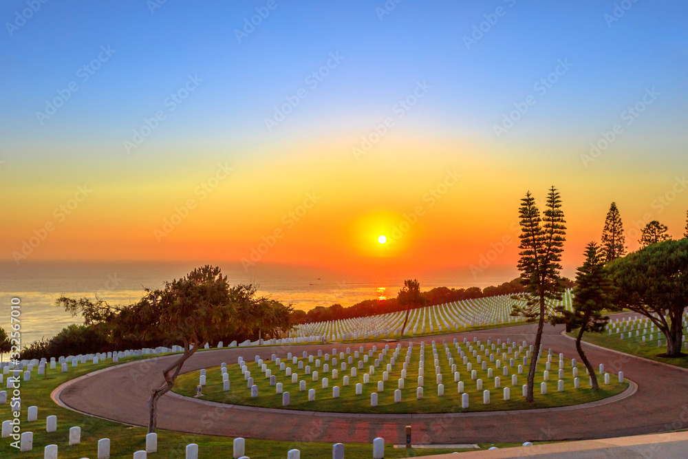 Cemetery graveyard white tombstones at sunset sky. American war cemetery in Point Loma, San Diego, California, United States with rows of gravestones oriented towards the ocean.