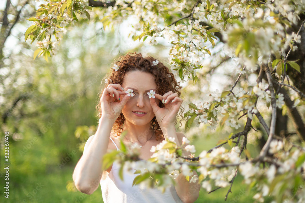 Young attractive girl walks in spring green park enjoying flowering nature. Healthy smiling girl spinning on the spring lawn. Allergy without Young attractive girl walks in spring green park enjoying flowering nature. Healthy smiling girl spinning on the spring lawn. Allergy without