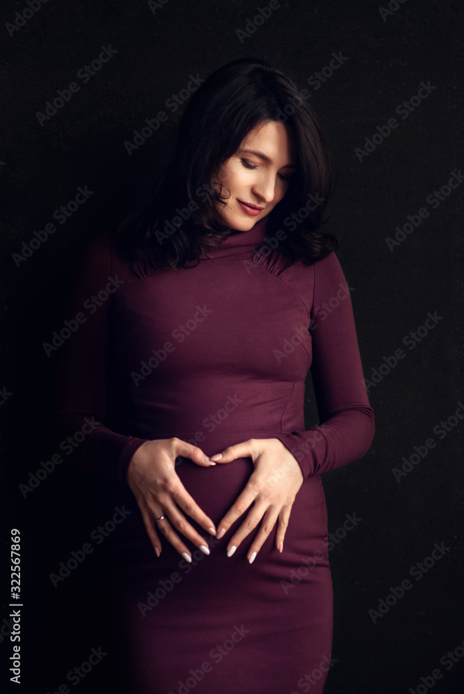 Obraz premium Pregnant happy Woman touching her belly. Pregnant middle aged mother portrait, caressing her belly and smiling close-up. Healthy Pregnancy concept, brunette expectant female 