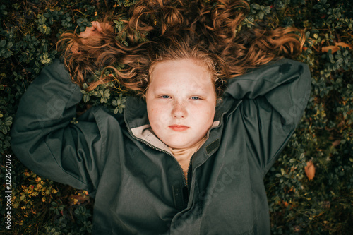 Portrait of pretty chubby girl lies on a grass photo