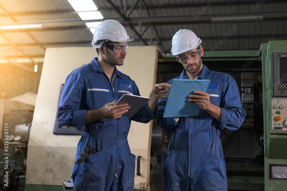 Two industrial workers operate lathes in the metalworking machinery industry. Industrial people meeting together in factory. Two industrial workers operate lathes in the metalworking machinery industry. Industrial people meeting together in factory.