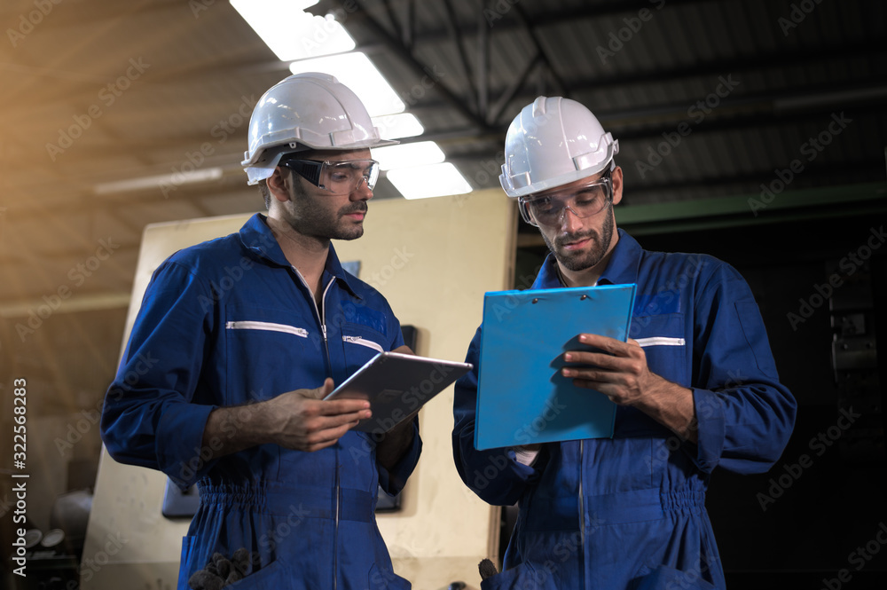 Fototapeta premium Two industrial workers operate lathes in the metalworking machinery industry. Industrial people meeting together in factory.