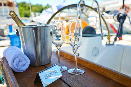 Romantic luxury evening on cruise yacht with champagne setting. Empty glasses and bottle with champagne and tropical sunset with sea background
