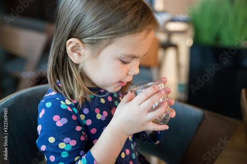 Little girl with glass of water in cafe
