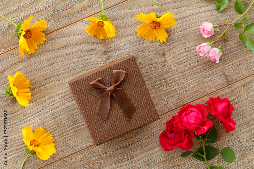 Gift box with flowers on the wooden background.