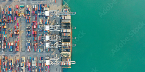 Aerial view. Container ship in pier with crane bridge carries out export and import business in the open sea. Logistics and transportation