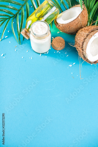 Coconut oil in glass jar with  tropical leaves and fresh coconut. Organic mct oils concept. turquoise, aquamarine background photo