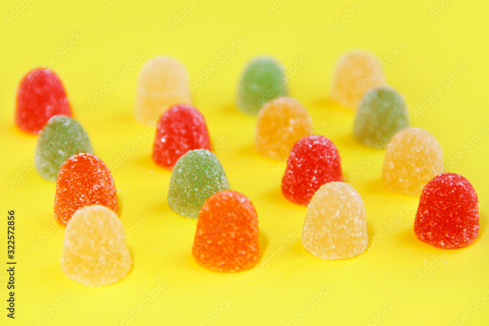 sweet round multicolored marmalade sweets in sugar sprinkles on a yellow background sweet round multicolored marmalade sweets in sugar sprinkles on a yellow background