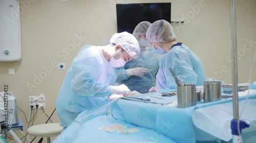 Two surgeons and two assistants perform surgery on the face. Sew a cut. Medicine, clinic