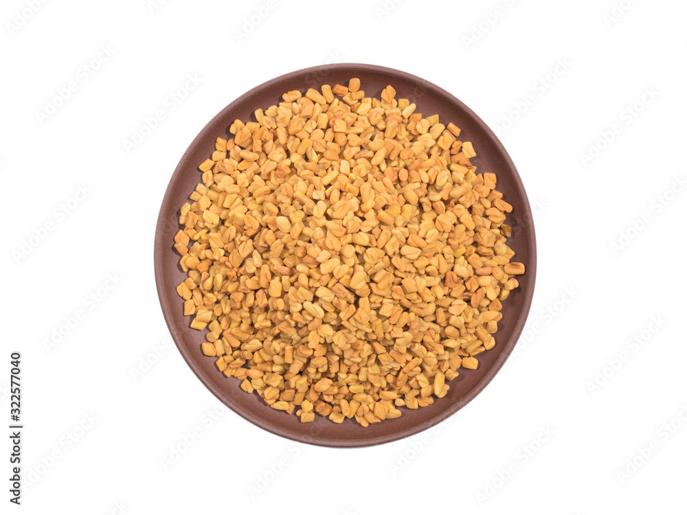 Spice fenugreek in clay plate isolated on white Spice fenugreek in clay plate isolated on white