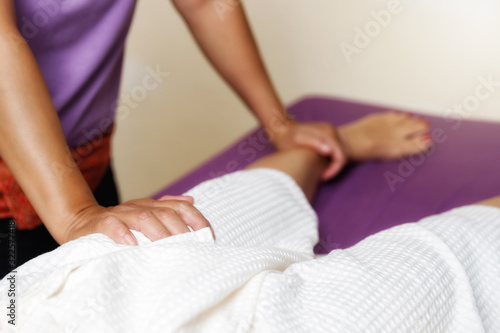 Woman receiving foot massage service from masseuse in spa salon thai spa and massage shop.