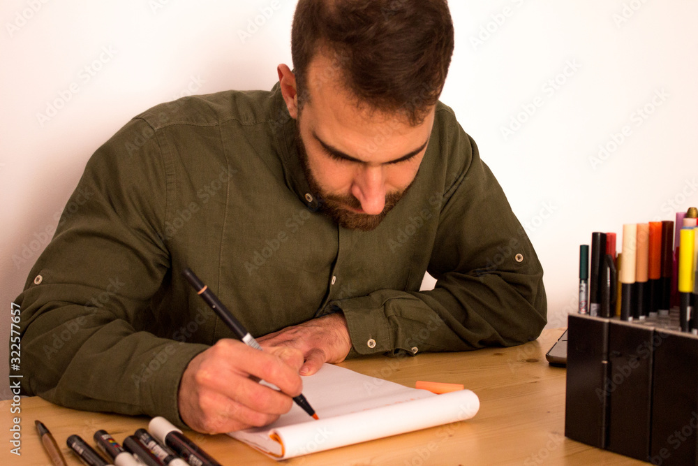 Young man doing lettering in his office Young man doing lettering in his office