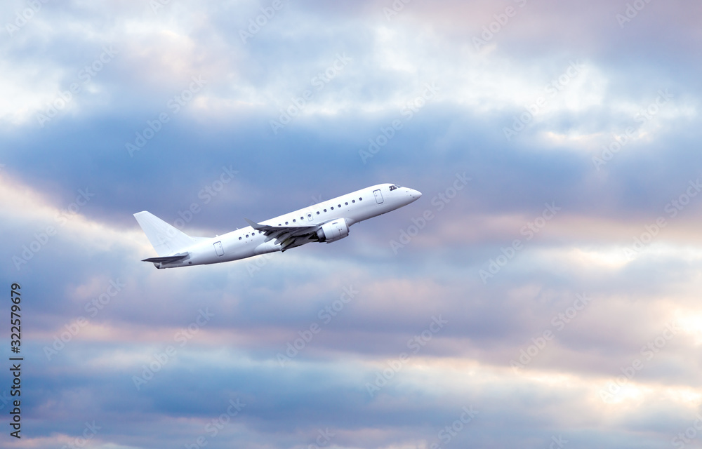 Fototapeta white jet aircraft in flight on cloudy sky background.