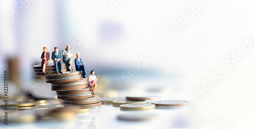 Miniature people: Elderly people sitting on coins stack. social security income and pensions. Money saving and Investment. Time counting down for retirement concept.