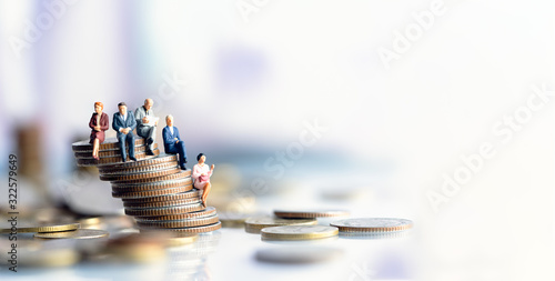 Miniature people: Elderly people sitting on coins stack. social security income and pensions. Money saving and Investment. Time counting down for retirement concept. photo