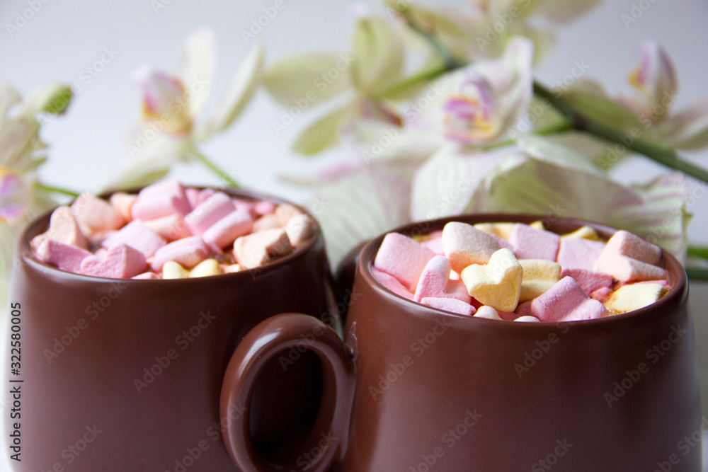 Brown cups of hot cocoa with marshmallows in heart shape on white background. Brown cups of hot cocoa with marshmallows in heart shape on white background.