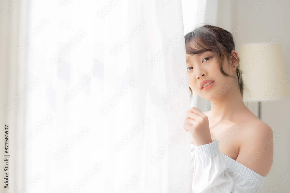 Portrait of beautiful young asian woman standing the window and smile while wake up with sunrise at morning, girl happy with freshness and cheerful, lifestyle and relax concept. Portrait of beautiful young asian woman standing the window and smile while wake up with sunrise at morning, girl happy with freshness and cheerful, lifestyle and relax concept.