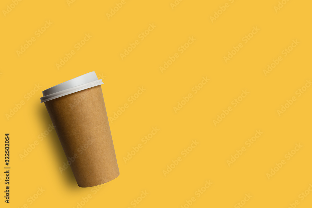 Simply flat lay design brown paper coffee cup isolated on yellow pastel colorful background Simply flat lay design brown paper coffee cup isolated on yellow pastel colorful background