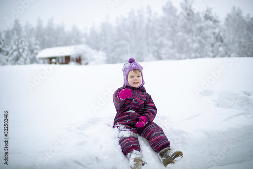 A small girl is sitting on the snow