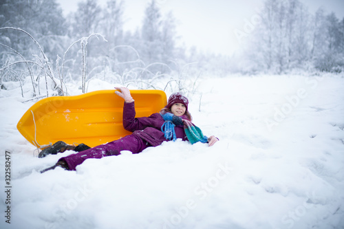Canvas Print A teen girl is lying on the snow with the sled