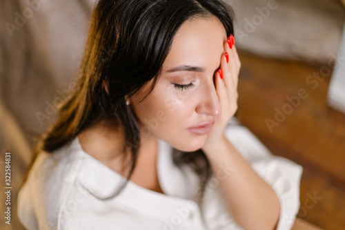 A beautiful oriental girl crying closes her eyes with her hand in a depressed state. Diagnosis psychiatrist treatment of the psyche. Depression stress insomnia bipolar disorder severe fatigue. Serious
