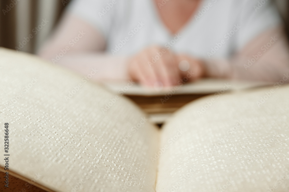 Fototapeta premium woman reading braille text on old book