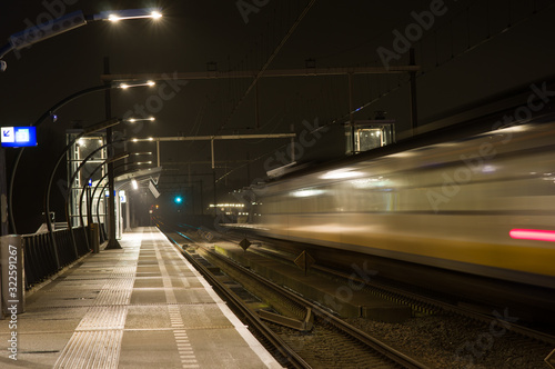 Blurred train by motion at night at station Arnhem south, Netherlands