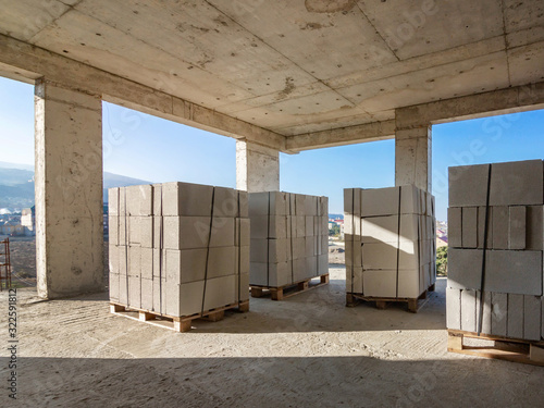 Several packages of aerated concrete blocks are randomly arranged in a building under construction