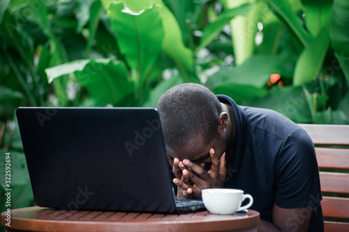 Serious pensive african businessman looking laptop in a coffee cafe