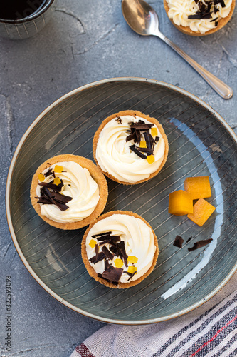 homemade shortbread tartlets or cupcakes with delicate cream and orange jam, decorated with chocolate chips. natural sweets concept. cozy tea party