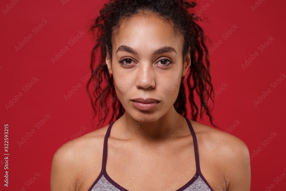 Close up of beautiful young african american sports fitness woman in sportswear posing working out isolated on red wall background in studio. Sport exercises healthy lifestyle concept. Looking camera. Close up of beautiful young african american sports fitness woman in sportswear posing working out isolated on red wall background in studio. Sport exercises healthy lifestyle concept. Looking camera.