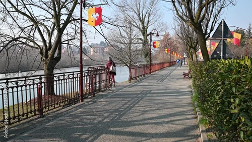 Ivrea, Italy, Piedmont. February 2020. The city is getting ready for the orange battle days. The flags of the districts are displayed everywhere. The riverside with the characteristic street lamps photo