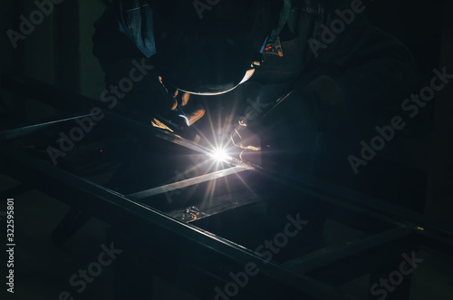 Welding a metal product in metal workshop. Bright glow of an electric arc. Fabrication of metal mounts photo