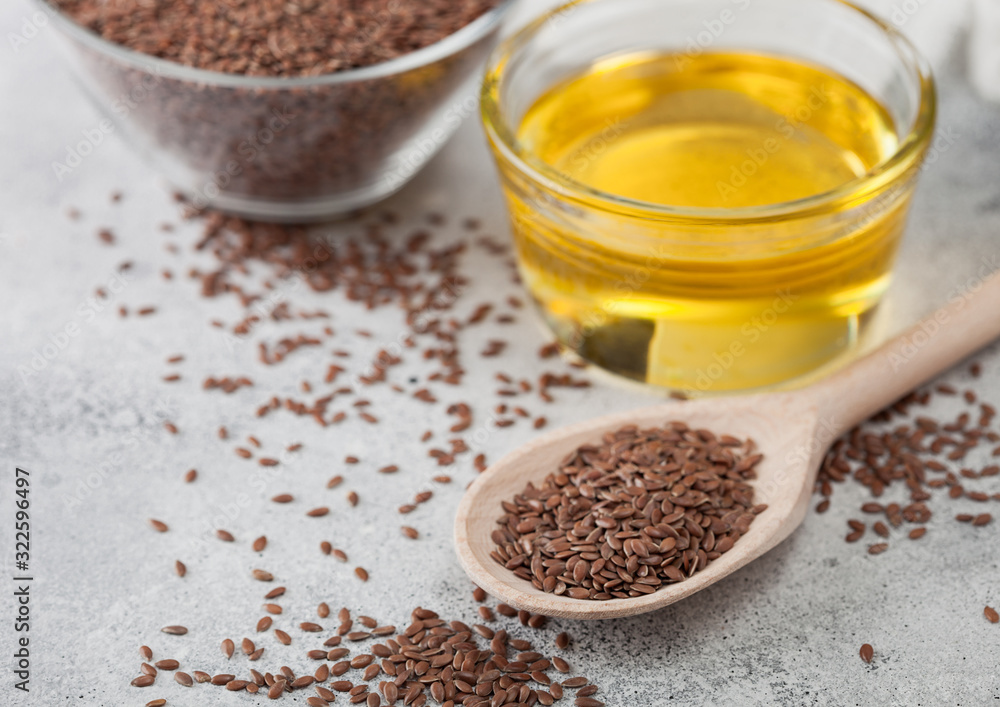 Bowl of raw natural organic linseed flax-seed with spoon and oil on light table background with linen cloth. Bowl of raw natural organic linseed flax-seed with spoon and oil on light table background with linen cloth.