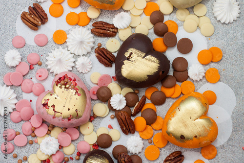 Canvas Print Assorted pink, orange, brown and green chocolate hearts with meringues, pecan nu