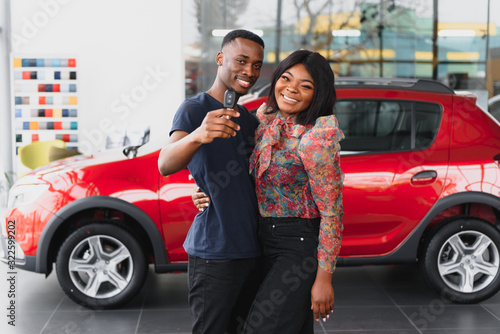 Фотография young african couple buying new car at dealership
