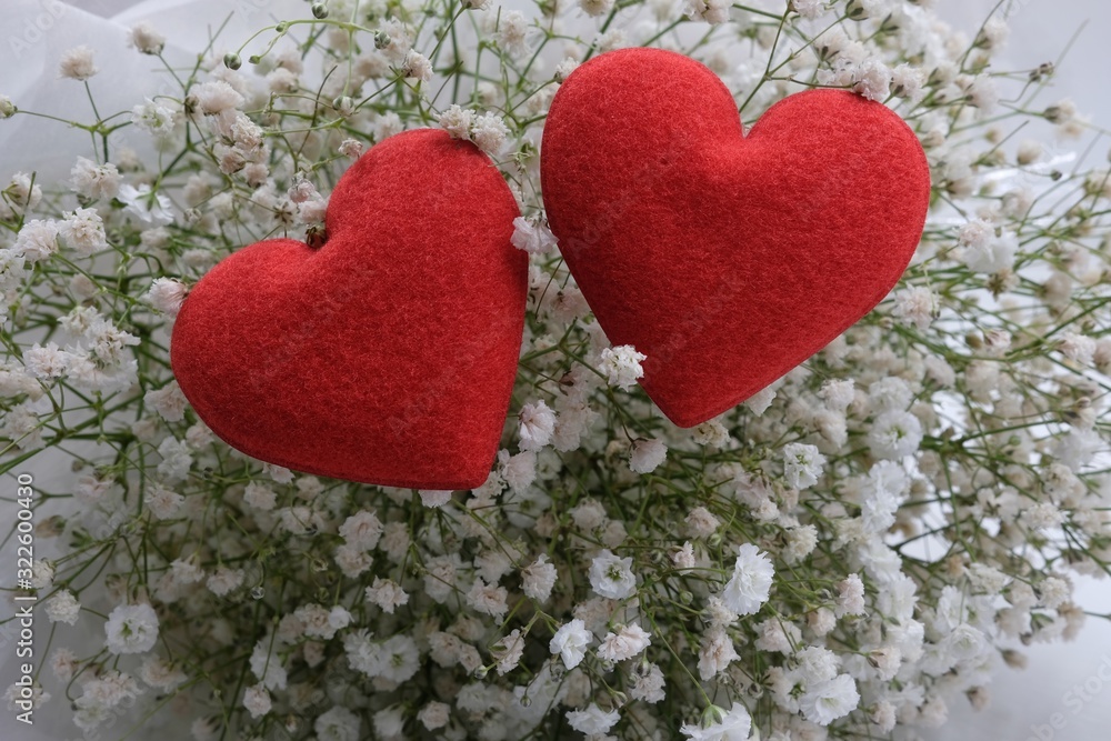 Two fabric red hearts shape place on white gypsophila flowers Two fabric red hearts shape place on white gypsophila flowers