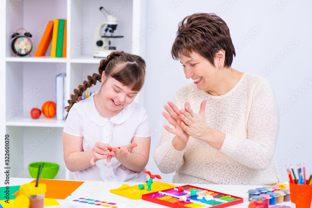 Fototapeta premium Girl with Down Syndrome works with her teacher at home