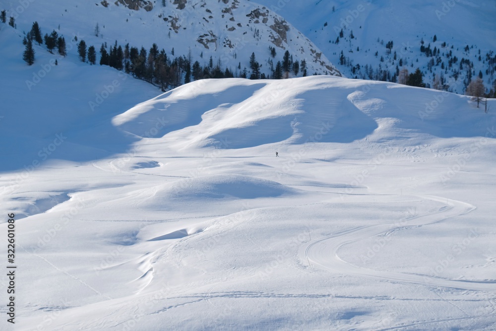 Winter mountain landscape with cross-country ski tracks and silhouette of running skier. Piazza Prato plateau, Sexten Dolomites, South Tyrol, Italy