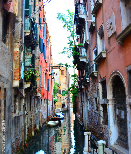 Narrow traditional Venetian canal street with empty boat, Venice, Italy