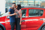 Smiling African American couple hugging and smiling at camera at new car showroom