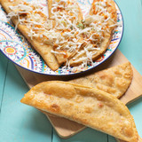 Mexican fried empanadas with cabbage and sauce on turquoise background