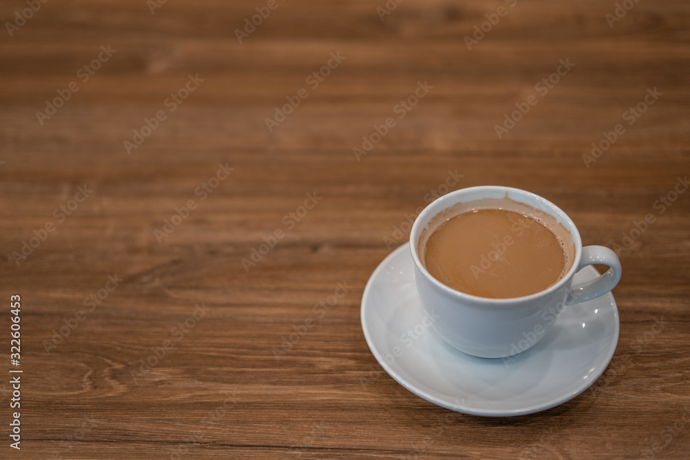The white ceramic coffee cup with coaster is placed on a brown wooden base on the back, naturally a blurred background. The white ceramic coffee cup with coaster is placed on a brown wooden base on the back, naturally a blurred background.