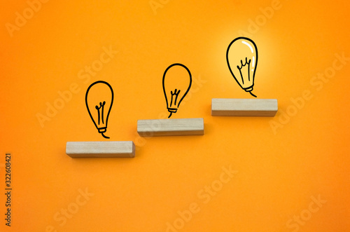 grow up chart with bulb light succeed wooden block on the orange background copy space © Artur Falgowski